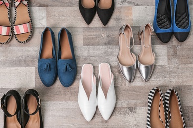 Different female shoes on wooden background, top view