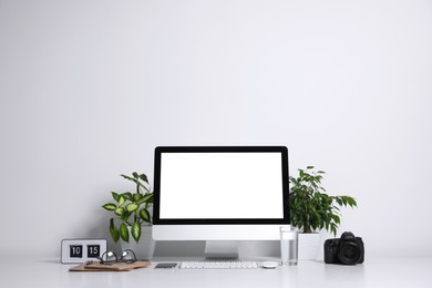 Photo of Comfortable workplace with modern computer on table near white wall. Space for text