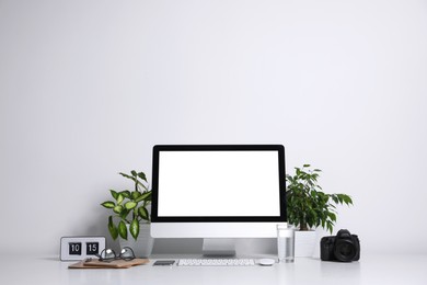 Comfortable workplace with modern computer on table near white wall. Space for text