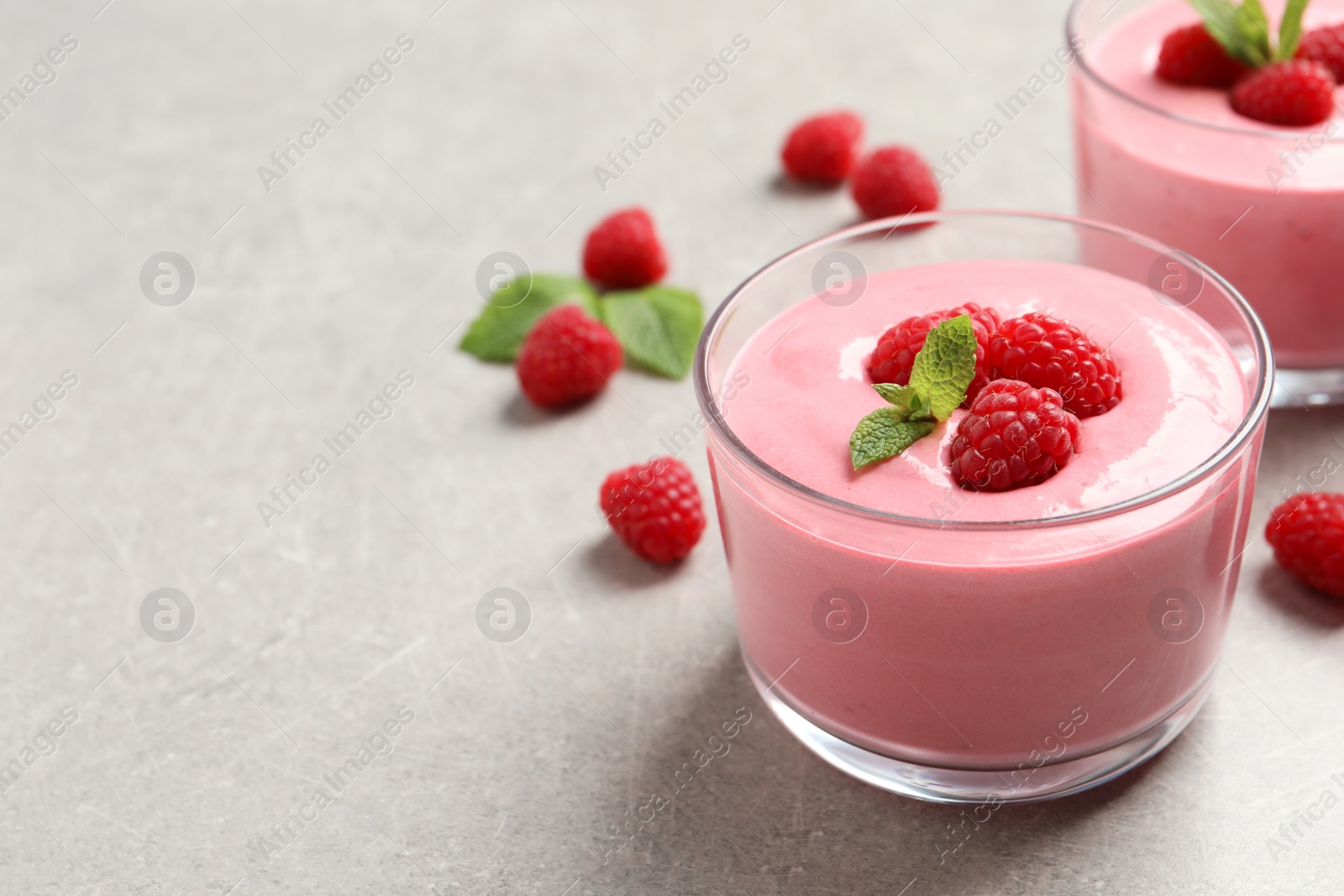 Photo of Delicious raspberry mousse with mint on light grey table, space for text