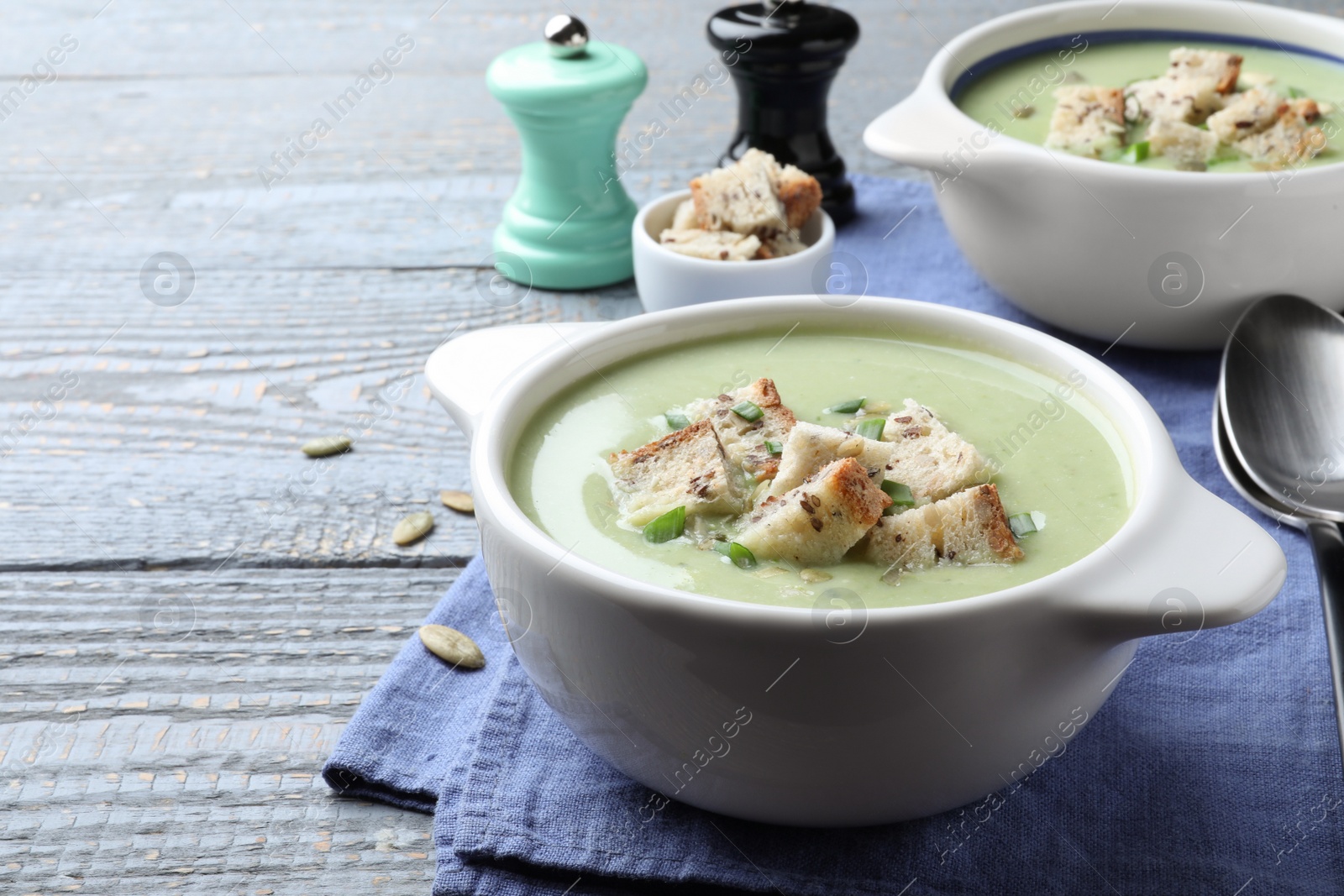 Photo of Delicious asparagus soup with croutons served on grey wooden table