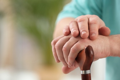 Closeup view of elderly man with cane in nursing home, space for text. Assisting senior generation