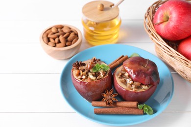 Photo of Tasty baked apples with nuts, honey, spices and mint on white wooden table