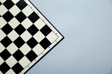 Photo of Black and white empty checkerboard on light grey background, top view. Space for text