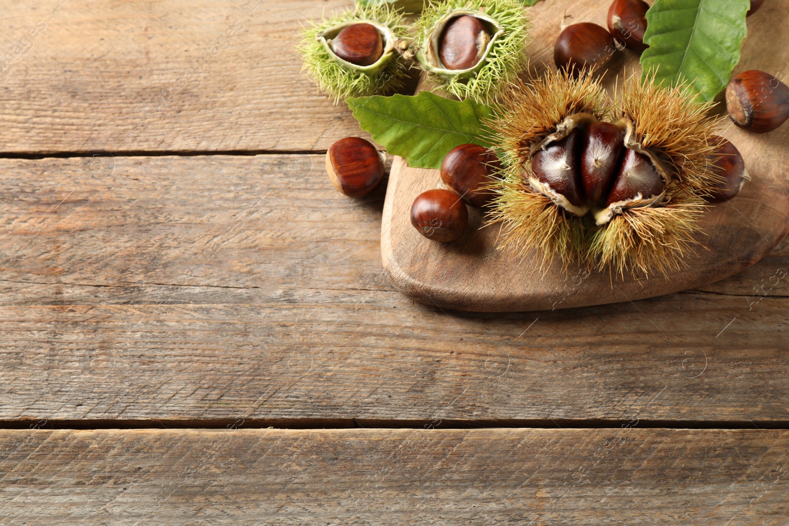 Photo of Fresh sweet edible chestnuts on wooden table, above view. Space for text