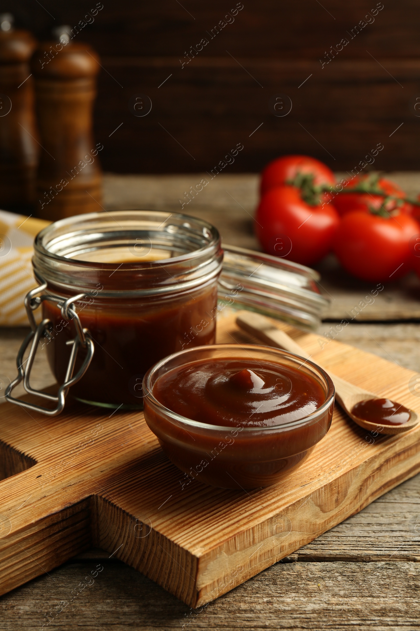 Photo of Tasty barbeque sauce in bowl, jar and spoon on wooden table