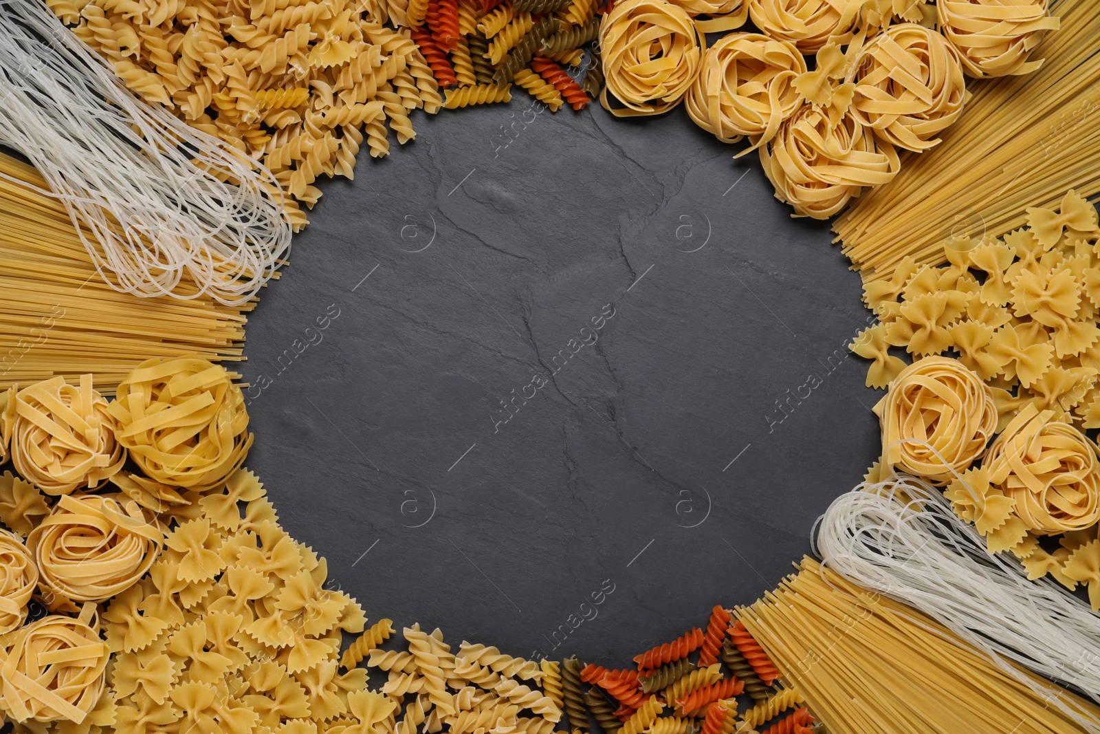 Photo of Frame made with different types of pasta on black table, top view. Space for text
