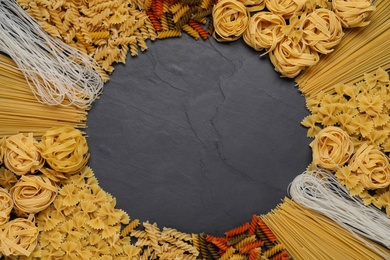 Frame made with different types of pasta on black table, top view. Space for text