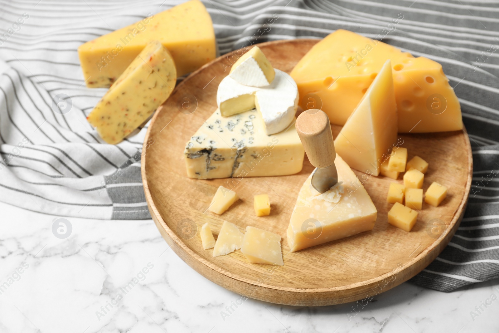 Photo of Different types of delicious cheese in wooden plate on marble table