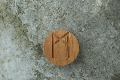 Photo of Wooden rune Mannaz on stone outdoors, closeup