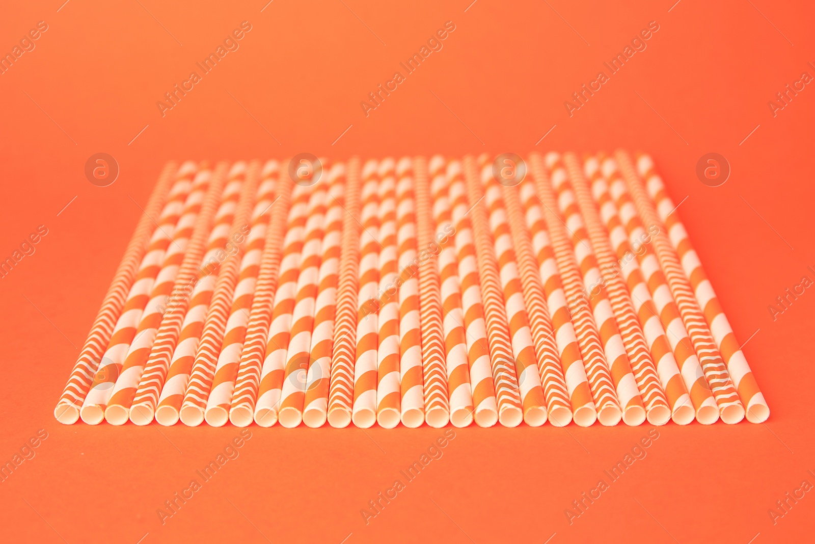 Photo of Many striped paper drinking straws on orange background