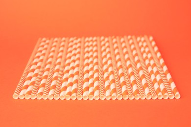 Many striped paper drinking straws on orange background