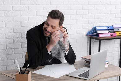 Businessman popping bubble wrap at workplace in office. Stress relief