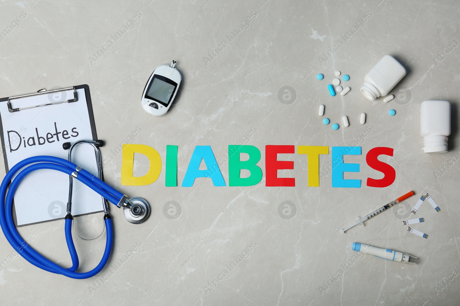Photo of Flat lay composition with word "Diabetes", digital glucometer, stethoscope and medicine on marble background