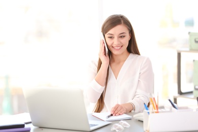 Young woman talking on phone at workplace