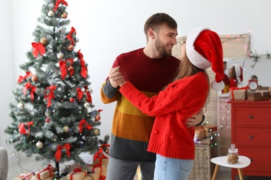 Happy young couple dancing near Christmas tree at home