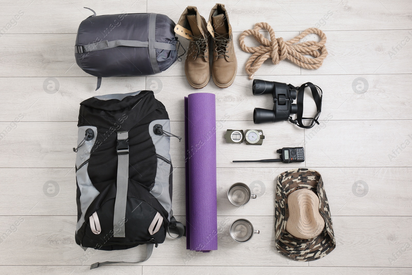 Photo of Flat lay composition with sleeping bag and camping equipment on wooden background