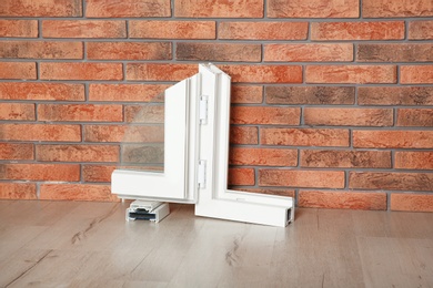 Photo of Sample of modern window profile on floor against brick wall. Installation service