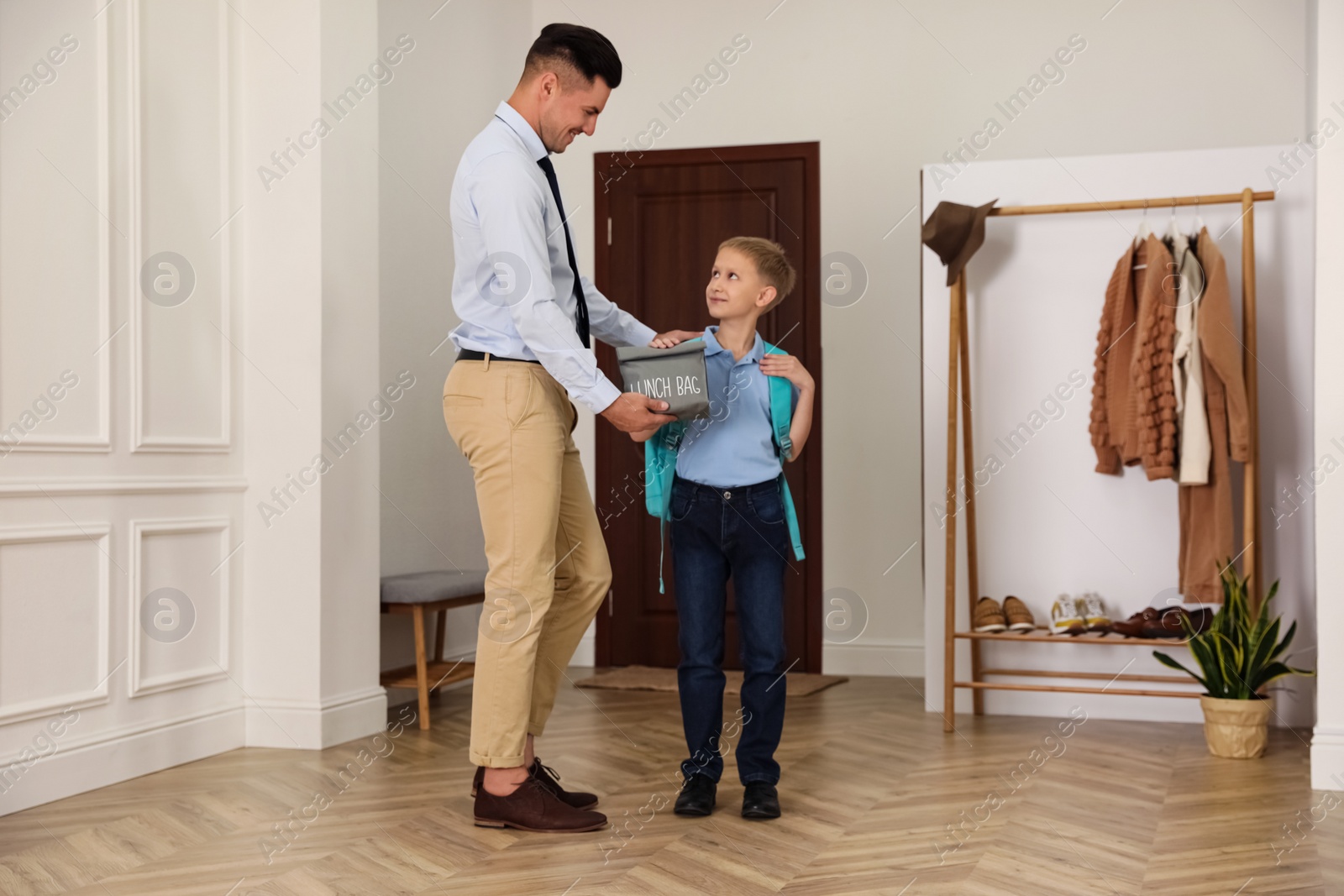 Photo of Father helping his little child get ready for school in hallway