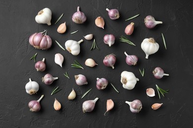 Photo of Fresh garlic and rosemary on dark textured table, flat lay