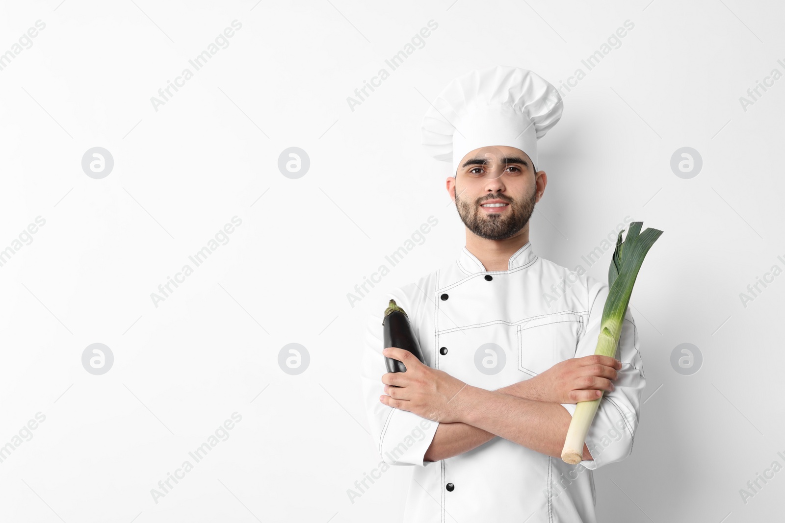Photo of Professional chef holding leek and eggplant on white background