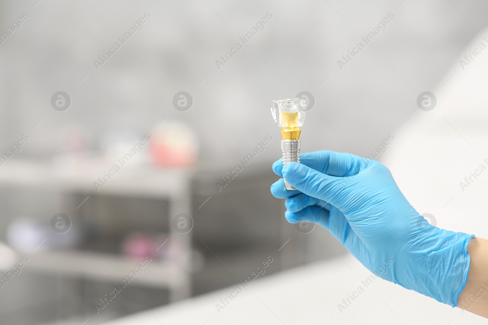 Photo of Dentist holding educational model of dental implant indoors, closeup. Space for text