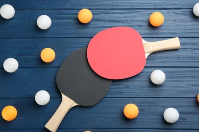 Photo of Ping pong rackets and balls on blue wooden table, flat lay