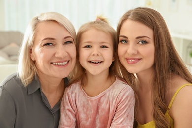 Photo of Happy young woman with her mother and daughter at home