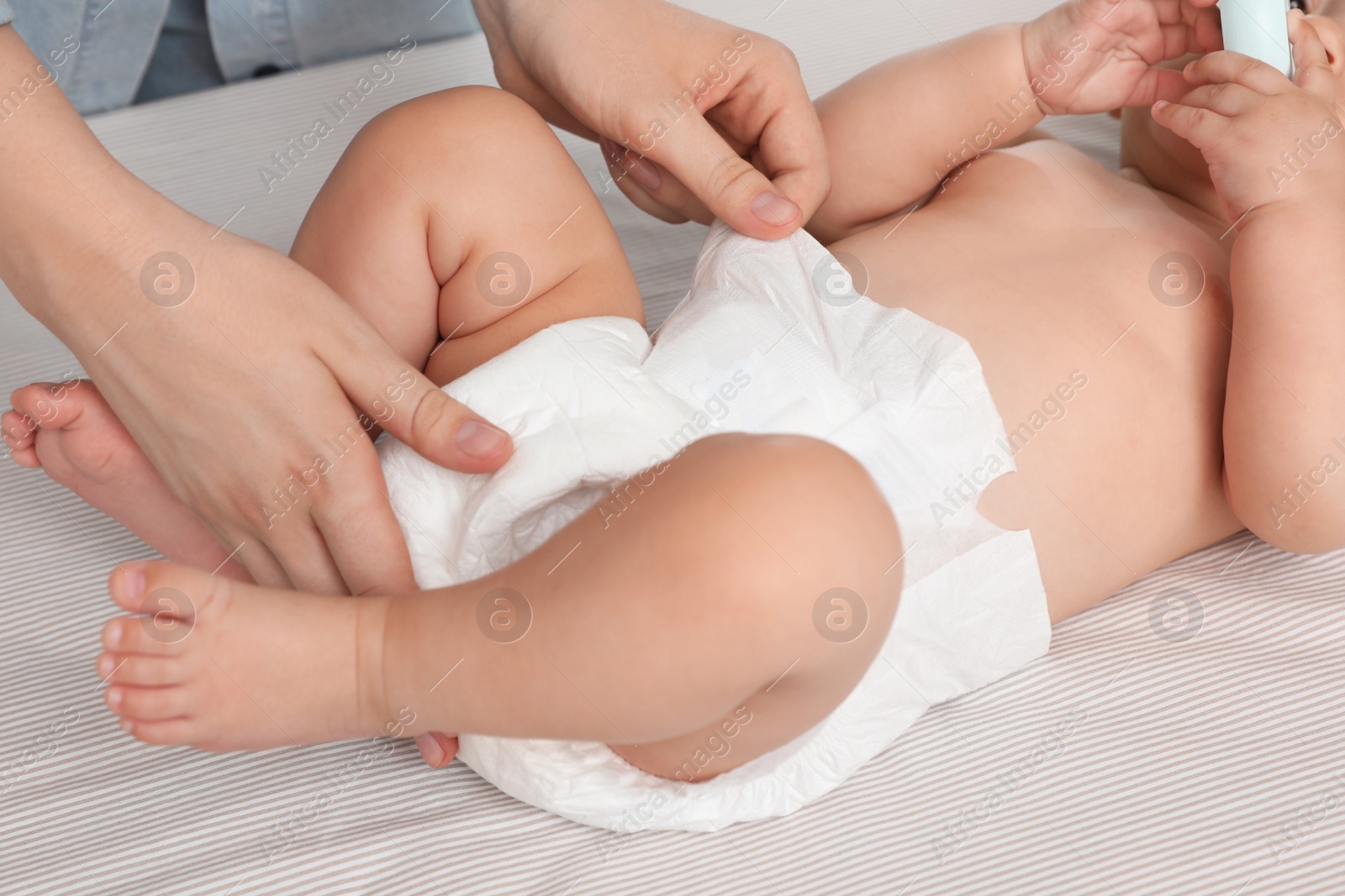 Photo of Mother changing baby's diaper on bed, closeup