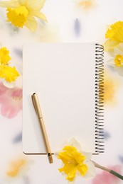 Photo of Guest list. Notebook, pen and daffodils on spring floral background, flat lay