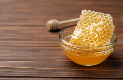 Photo of Tasty fresh honeycomb in bowl on wooden table