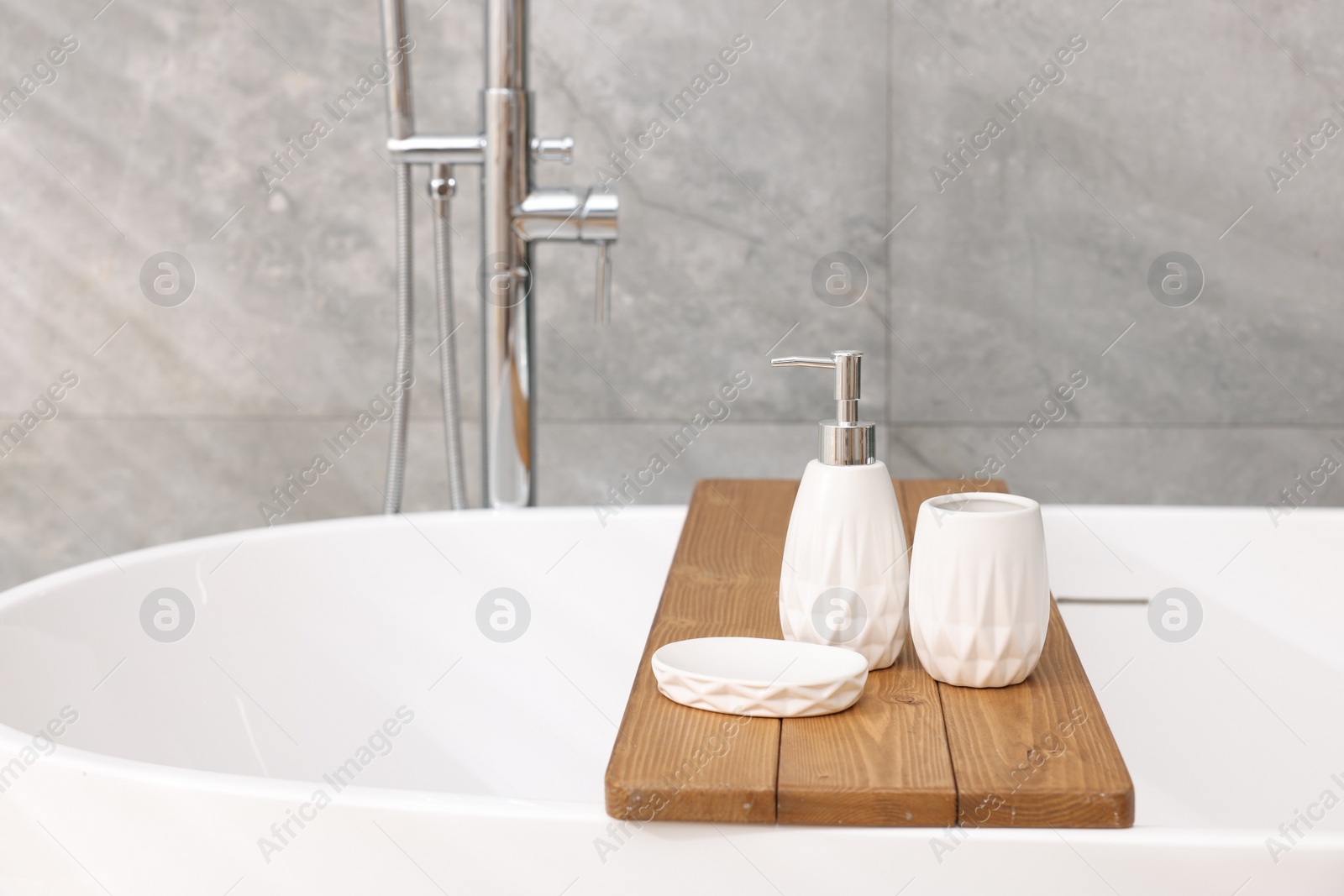 Photo of Set of bath accessories on tub in bathroom, space for text