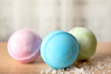 Colorful bath bombs and cosmetic salt on wooden table