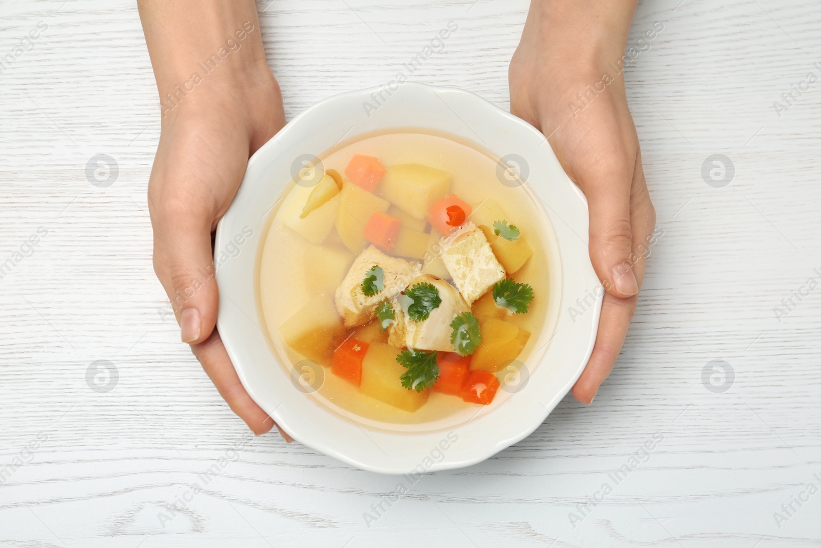 Photo of Woman eating fresh homemade chicken soup at table, top view