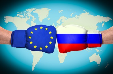 Image of Men in boxing gloves with European union and Russian flags fighting with world map on background, closeup. Political feud