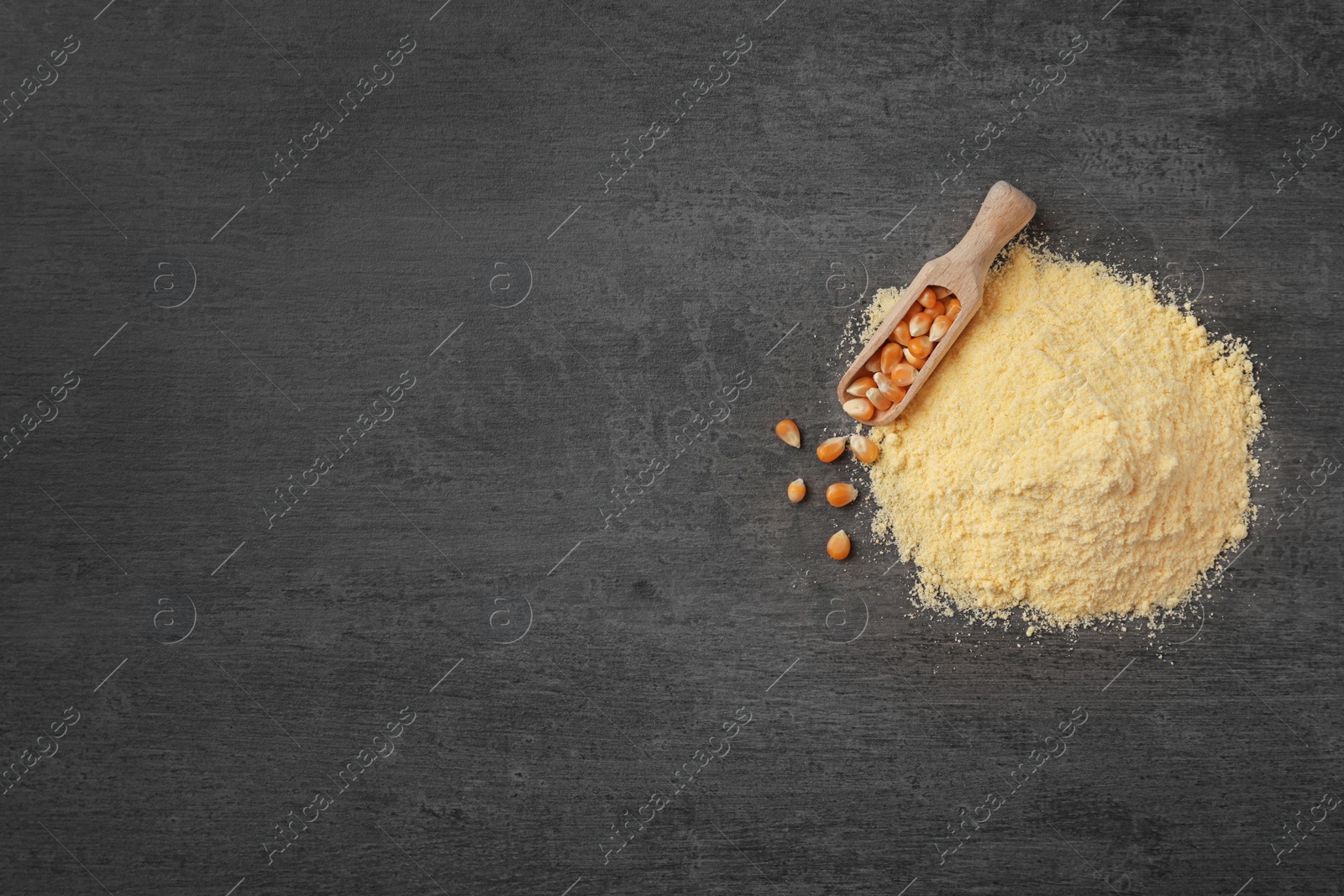 Photo of Pile of corn flour and scoop with kernels on gray background