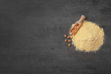 Photo of Pile of corn flour and scoop with kernels on gray background