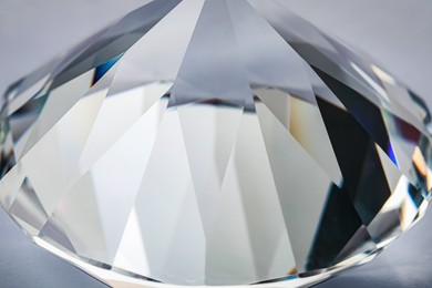 Photo of Beautiful dazzling diamond on light grey background, closeup. Precious gemstone