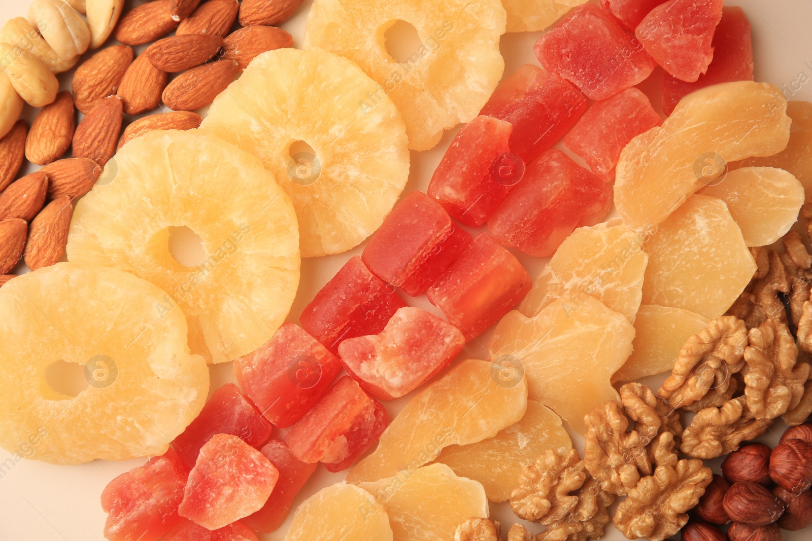 Photo of Different tasty nuts and dried fruits on beige background, flat lay