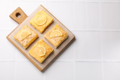 Photo of Tasty lemon bars on white tiled table, top view. Space for text