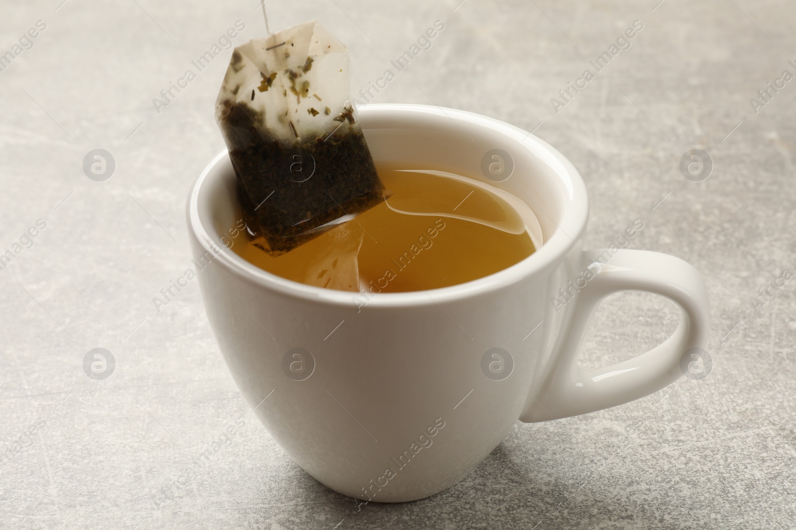Photo of Taking tea bag out of cup with at light table, closeup