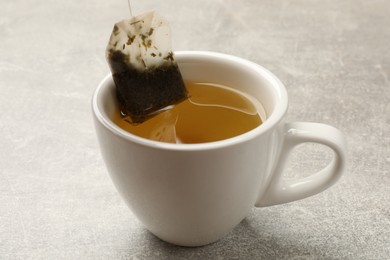 Photo of Taking tea bag out of cup with at light table, closeup