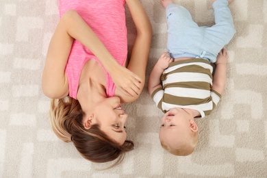 Photo of Young woman with her son lying on floor at home, top view