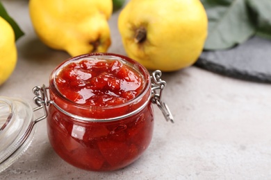 Delicious quince jam on light grey table, closeup