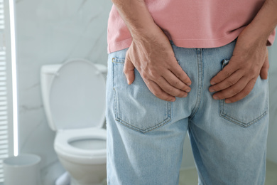 Man suffering from hemorrhoid in rest room, closeup