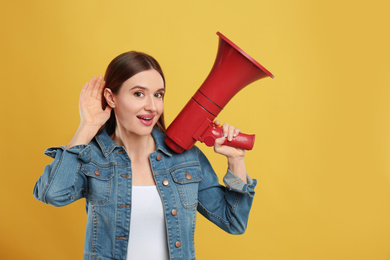 Photo of Young woman with megaphone on yellow background