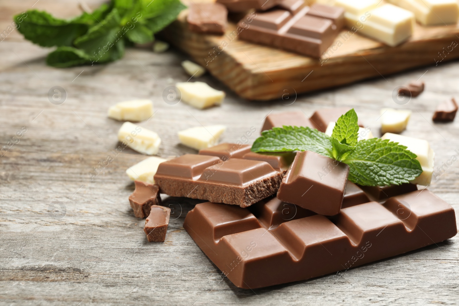 Photo of Different kinds of chocolate with mint on wooden table