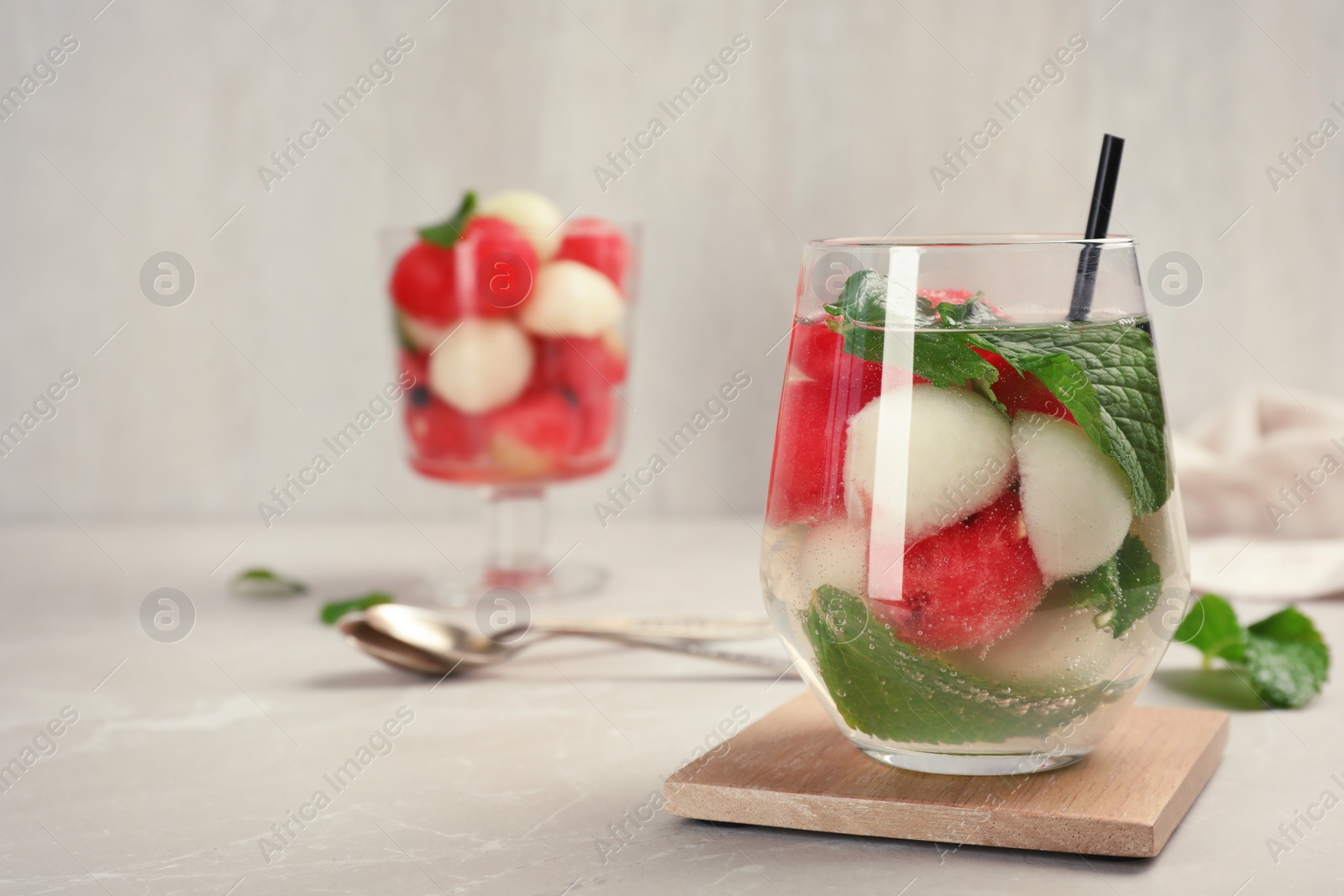 Photo of Glass with tasty melon and watermelon ball drink on gray table