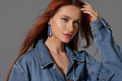 Beautiful young woman in denim jacket on gray background