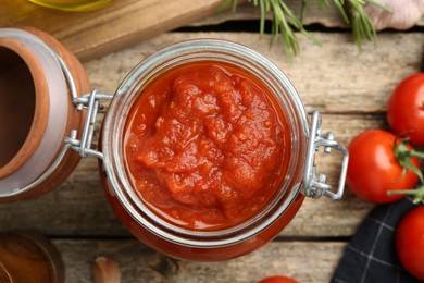 Homemade tomato sauce in jar on wooden table, top view